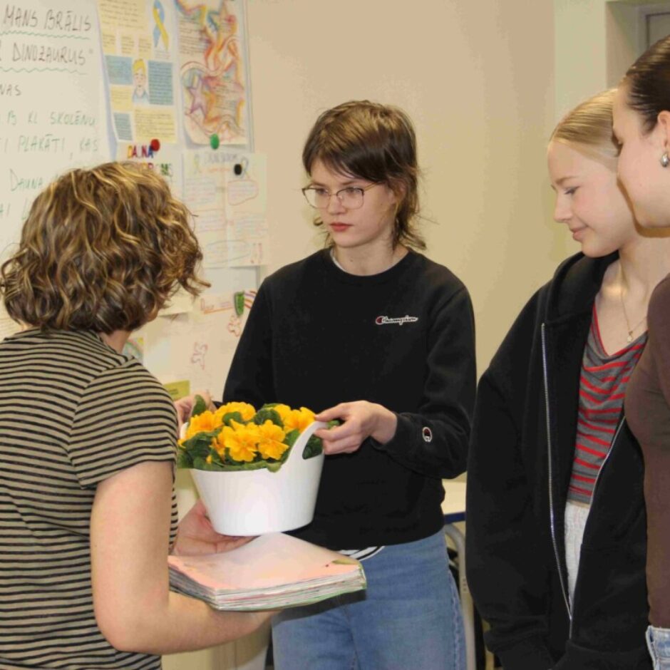 skolēni pasniedz ziedus rakstniecei