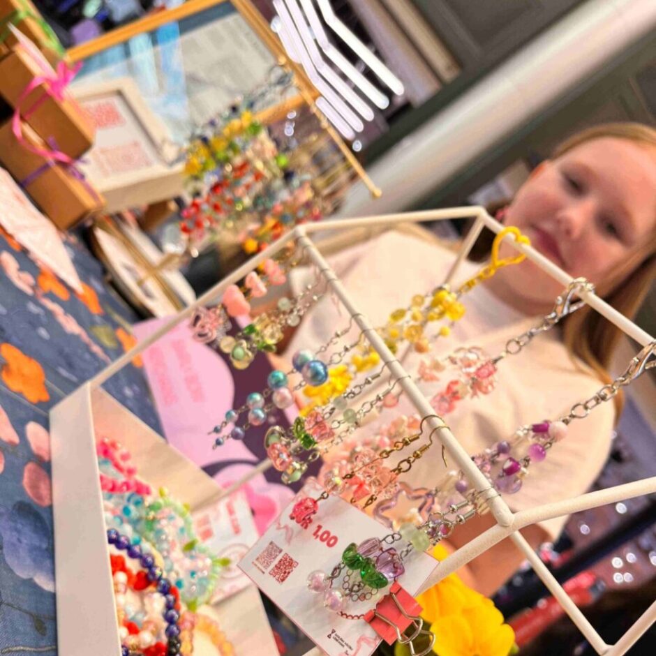 Simply Bow Keychains stends ar Patrīciju fonā