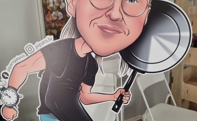 Liels kartona izgriezums, kas attēlo karikatūras vīrieti ar sirmiem matiem, brillēm, smaidu un zilu acīm. Viņš tērpies melnā T-kreklā un garā melnā priekšautā, labajā rokā tur lielu melnu pannu, bet uz kreisās rokas ir liels pulkstenis. Blakus pulkstenim redzams teksts 