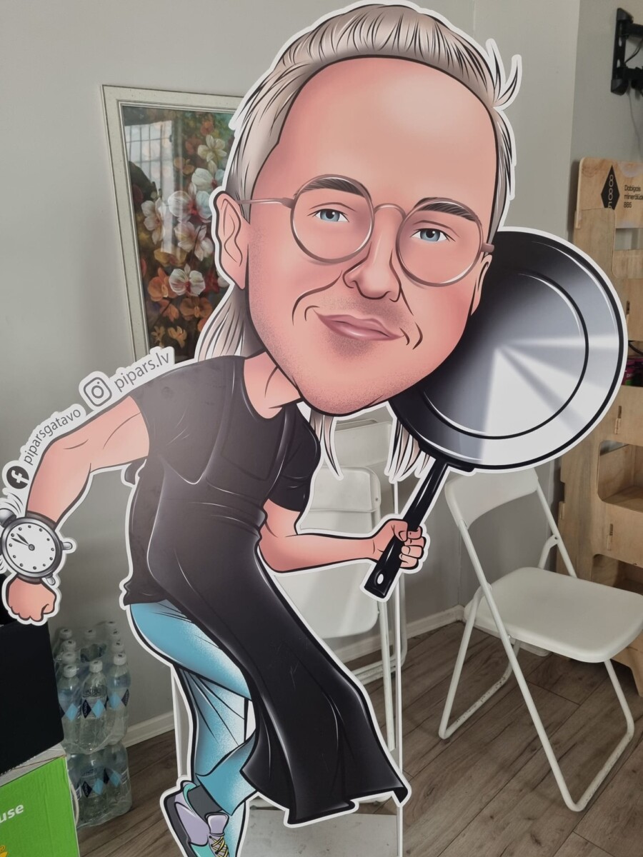 Liels kartona izgriezums, kas attēlo karikatūras vīrieti ar sirmiem matiem, brillēm, smaidu un zilu acīm. Viņš tērpies melnā T-kreklā un garā melnā priekšautā, labajā rokā tur lielu melnu pannu, bet uz kreisās rokas ir liels pulkstenis. Blakus pulkstenim redzams teksts 