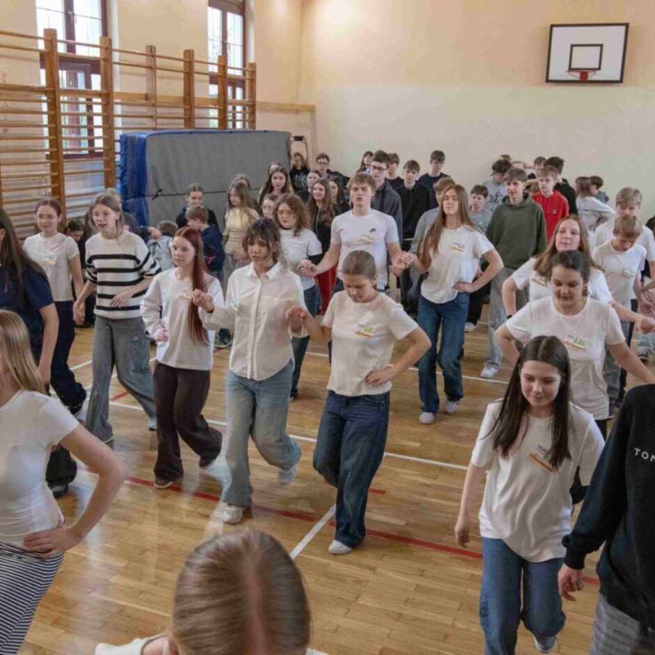 skolēni dejo dejas tērpušies baltos t-kreklos