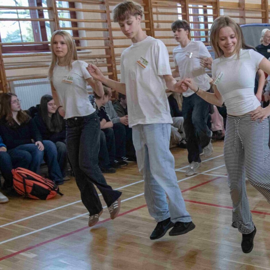 skolēni dejo dejas tērpušies baltos t-kreklos