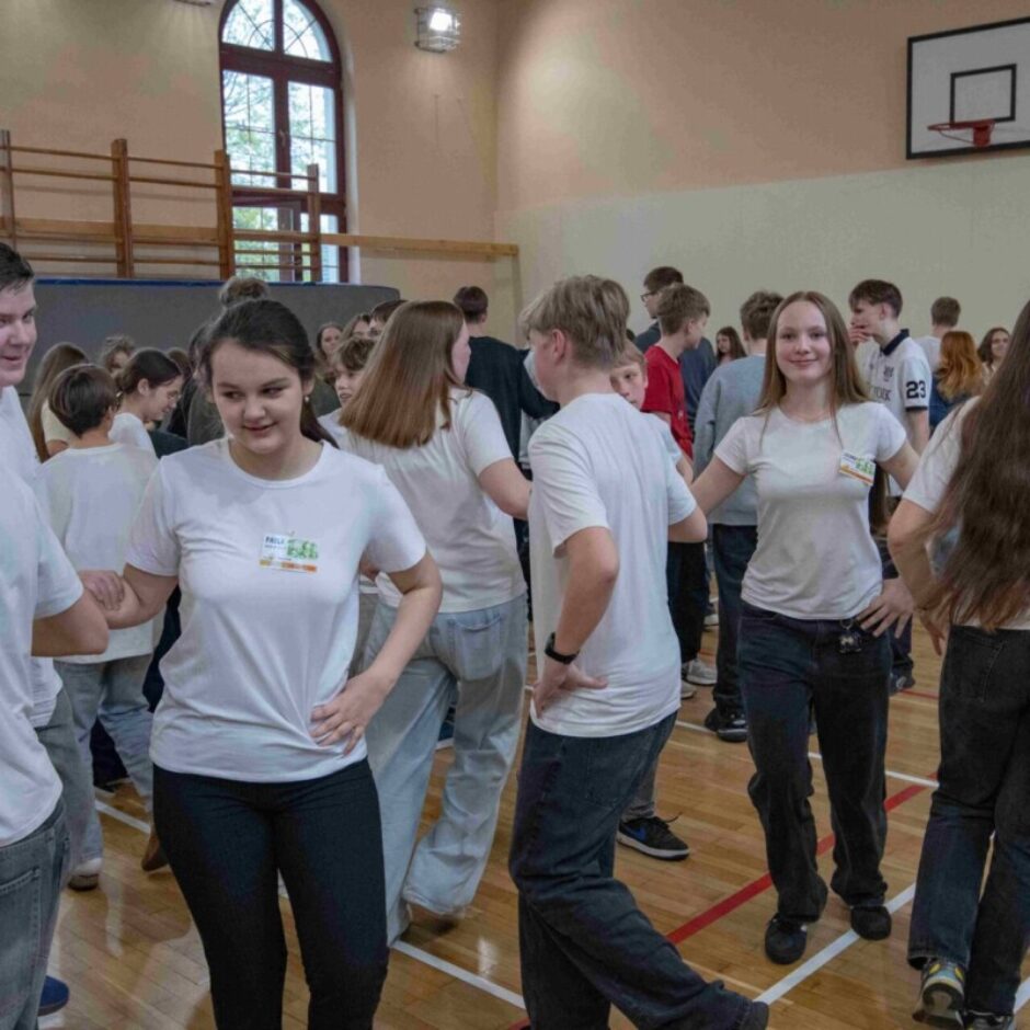 skolēni dejo dejas tērpušies baltos t-kreklos